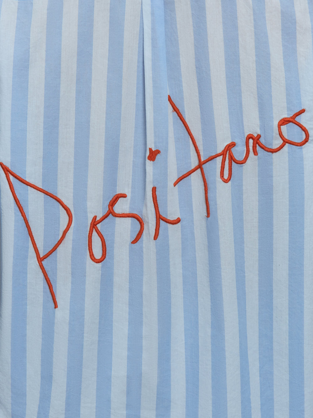 Model wears a striped blue and white buttondown long sleeve with single chest pocket. 