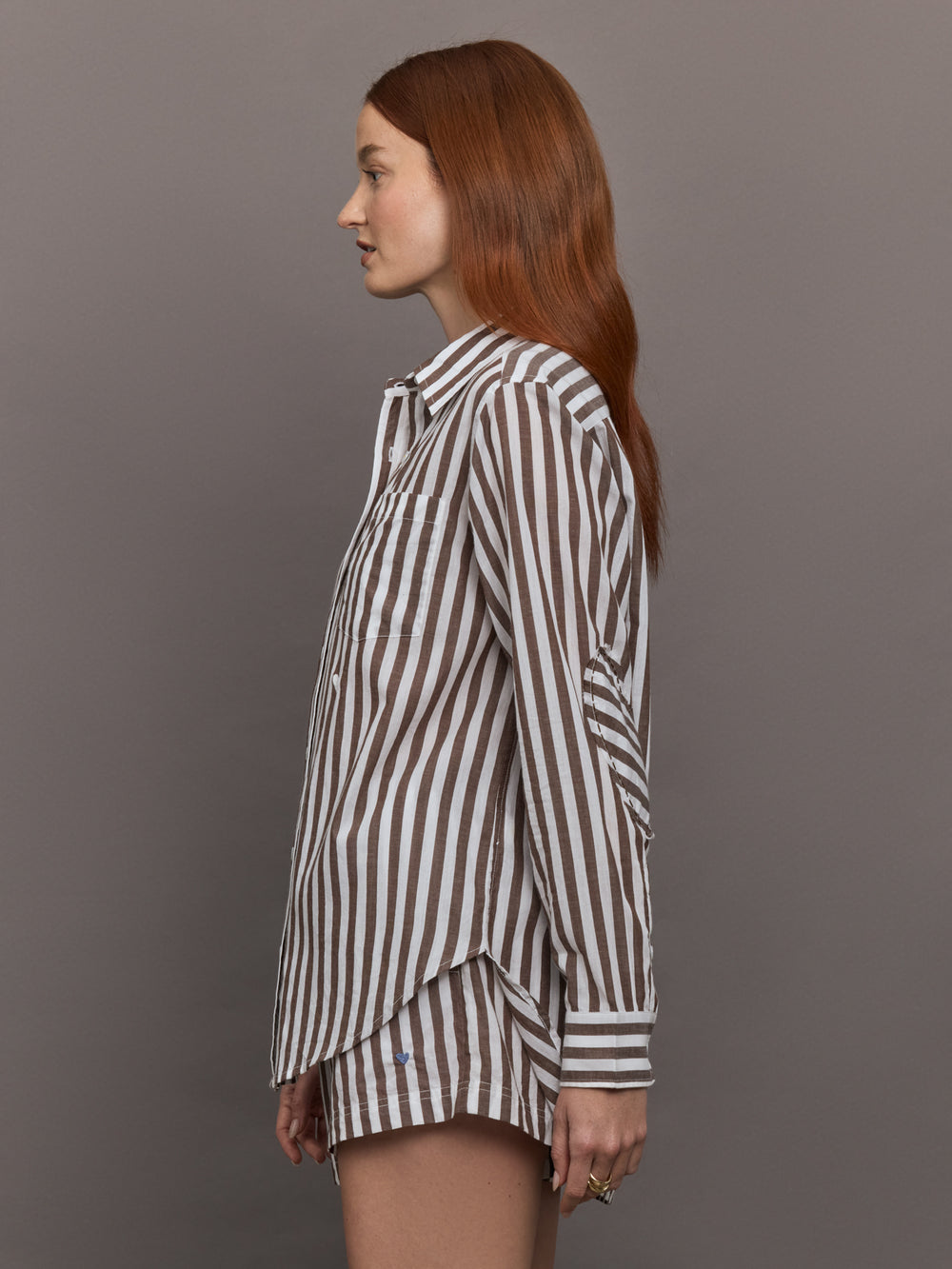 Model wears brown and white striped button-down shirt with a relaxed fit, long sleeves.