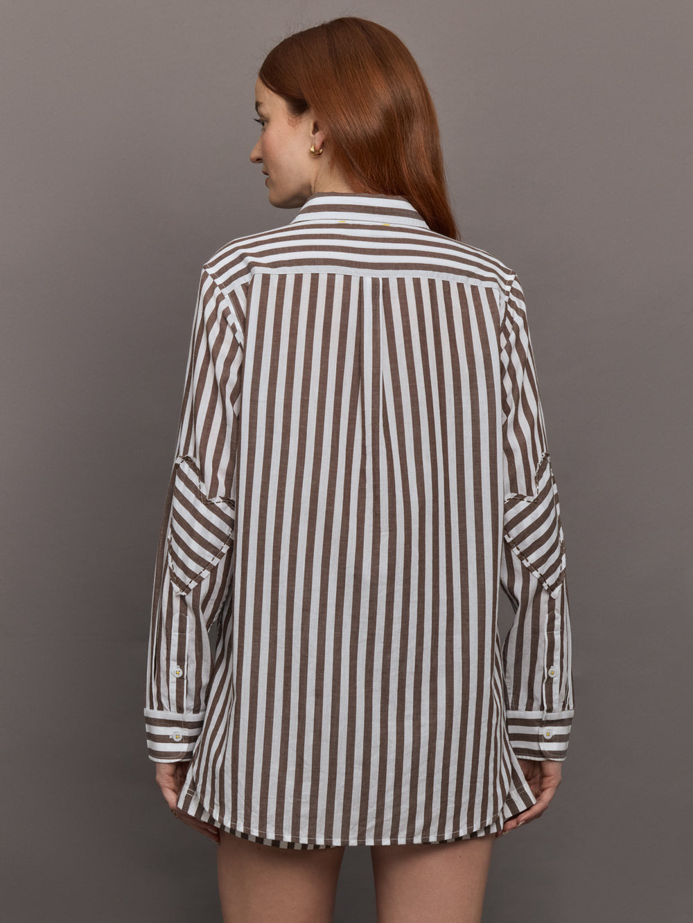 Model wears brown and white striped button-down shirt with a relaxed fit, long sleeves.