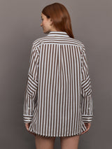 Model wears brown and white striped button-down shirt with a relaxed fit, long sleeves.