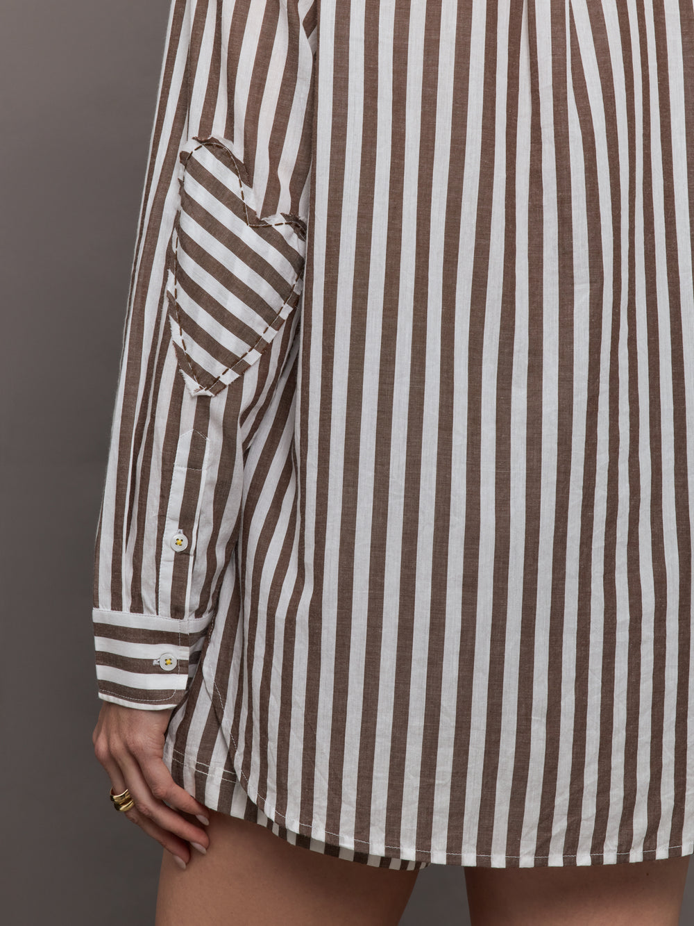 Model wears brown and white striped button-down shirt with a relaxed fit, long sleeves.