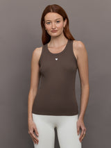 Model wears sleeveless tank top in a cocoa brown, featuring a scoop neckline and fitted silhouette and white heart in the upper center.