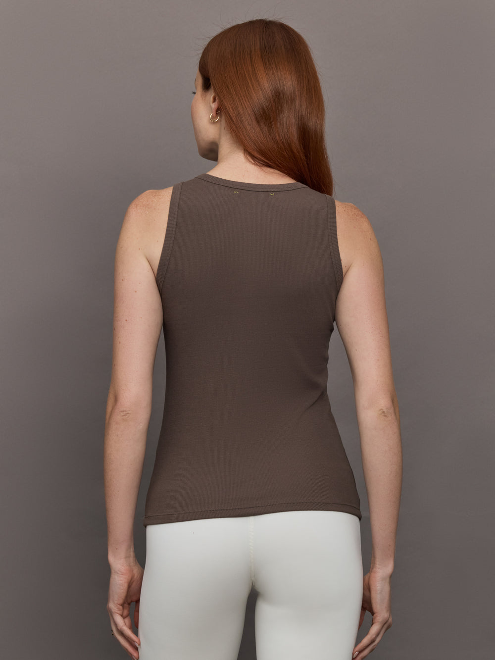 Model wears sleeveless tank top in a cocoa brown, featuring a scoop neckline and fitted silhouette and white heart in the upper center.