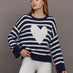 Model wears sweater in indigo and white featuring an abstract, imperfect heart design on the front, with long sleeves and a relaxed fit.