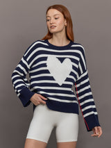 Model wears sweater in indigo and white featuring an abstract, imperfect heart design on the front, with long sleeves and a relaxed fit.