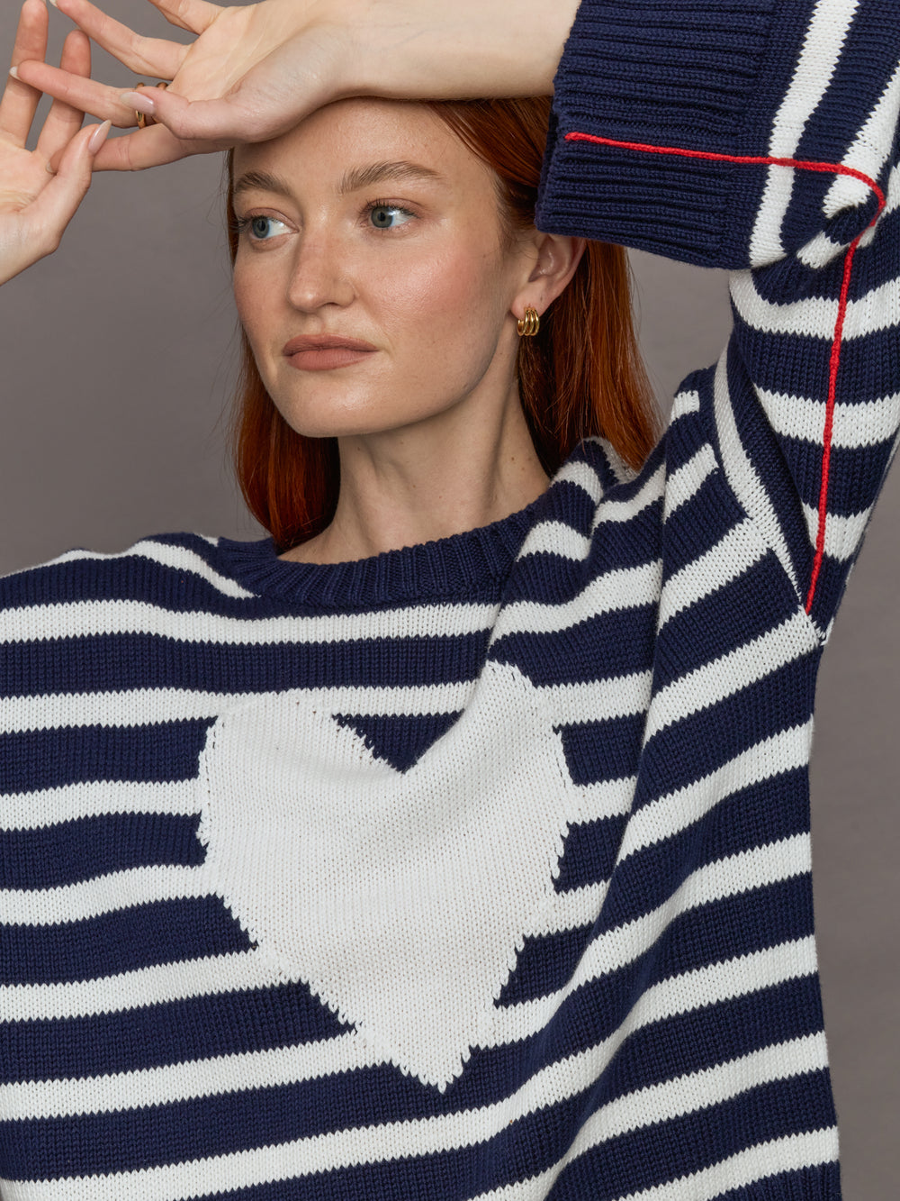 Model wears sweater in indigo and white featuring an abstract, imperfect heart design on the front, with long sleeves and a relaxed fit.