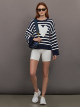 Model wears sweater in indigo and white featuring an abstract, imperfect heart design on the front, with long sleeves and a relaxed fit.