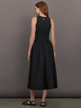 Model wears sleeveless black tank dress with a scoop neckline and lower waist drop.