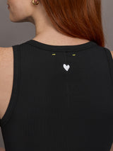 Model wears sleeveless black tank dress with a scoop neckline and lower waist drop.