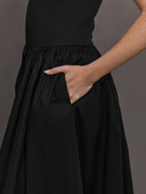 Model wears sleeveless black tank dress with a scoop neckline and lower waist drop.