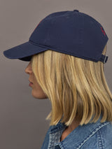 Person wearing a navy blue cap with a red logo on a gray background