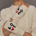 Person wearing a beige sweater with beige gloves that say "LOVE" with a red heart detail.