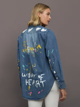 Woman wearing a blue denim shirt with artistic designs and text on a gray background