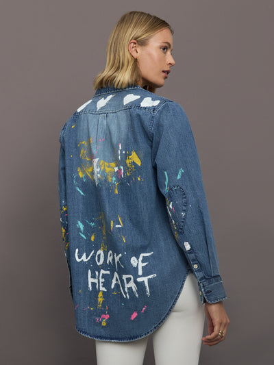 Woman wearing a blue denim shirt with artistic designs and text on a gray background