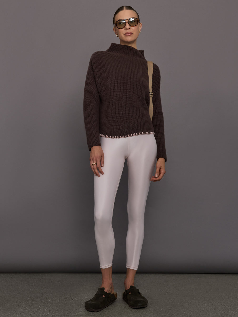 Person wearing a brown ribbed sweater and white leggings 