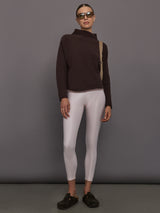 Person wearing a brown ribbed sweater and white leggings 