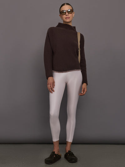 Person wearing a brown ribbed sweater and white leggings 
