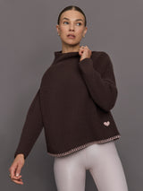Woman wearing a brown ribbed sweater with a pink heart detail 
