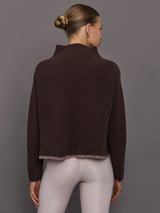 Person wearing a brown ribbed sweater with light pink detail