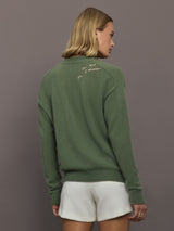 Woman wearing a green sweater with text on the back against a gray background