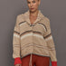 Beige knitted cardigan with patterned design and red cuffs on a neutral background