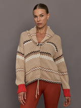 Beige knitted cardigan with patterned design and red cuffs on a neutral background