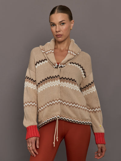 Beige knitted cardigan with patterned design and red cuffs on a neutral background
