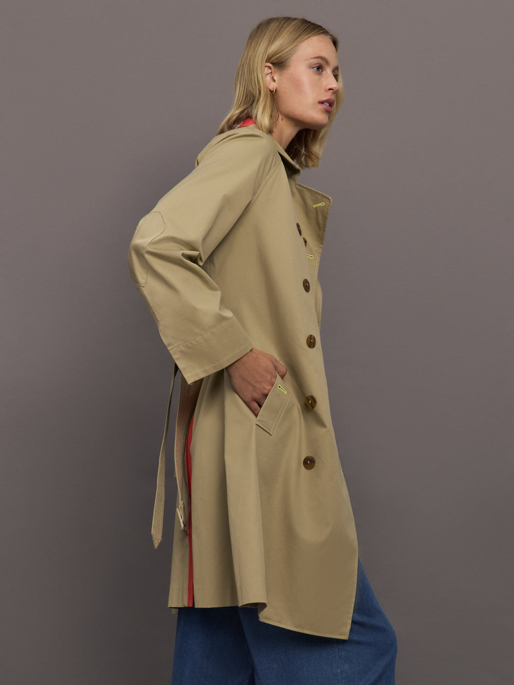 Woman wearing a beige trench coat with a gray background