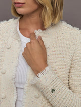 Close-up of a person wearing a textured beige cardigan over a white shirt.