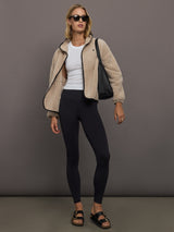 Model wears a camel colored fleece jacket with black embroidered heart on chest and elbows. 