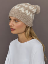 Model wearing camel alpaca-merino beanie with ivory hearts, front angle view.