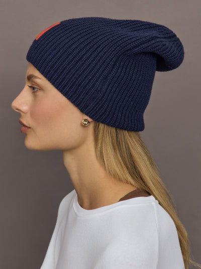 Side profile of indigo blue beanie on model, ribbed knit texture visible.