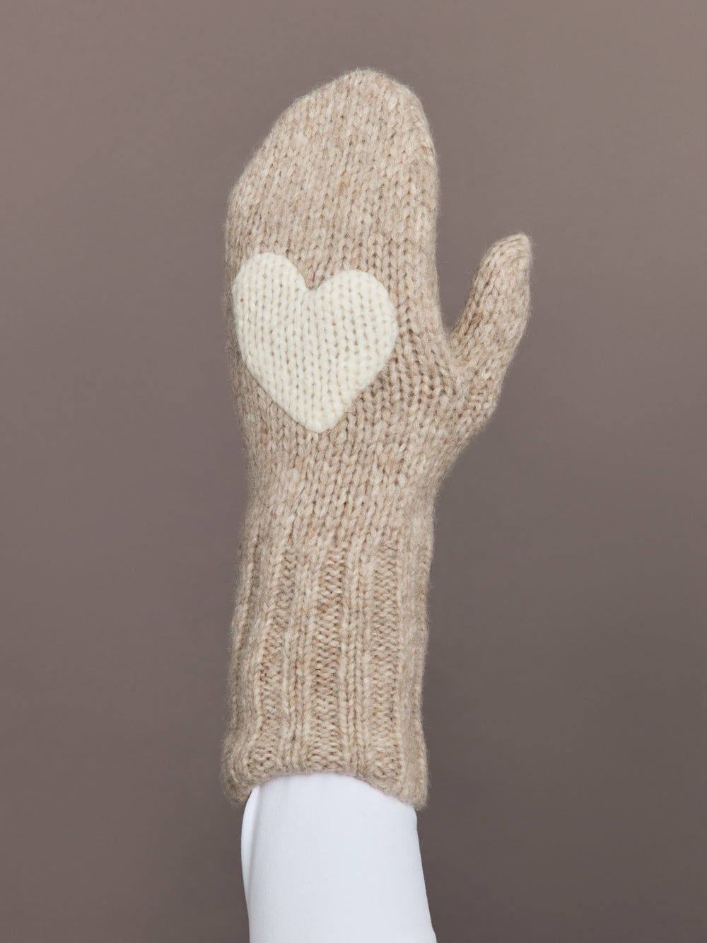 Close-up of camel knit mitten with cream heart patch, front view.