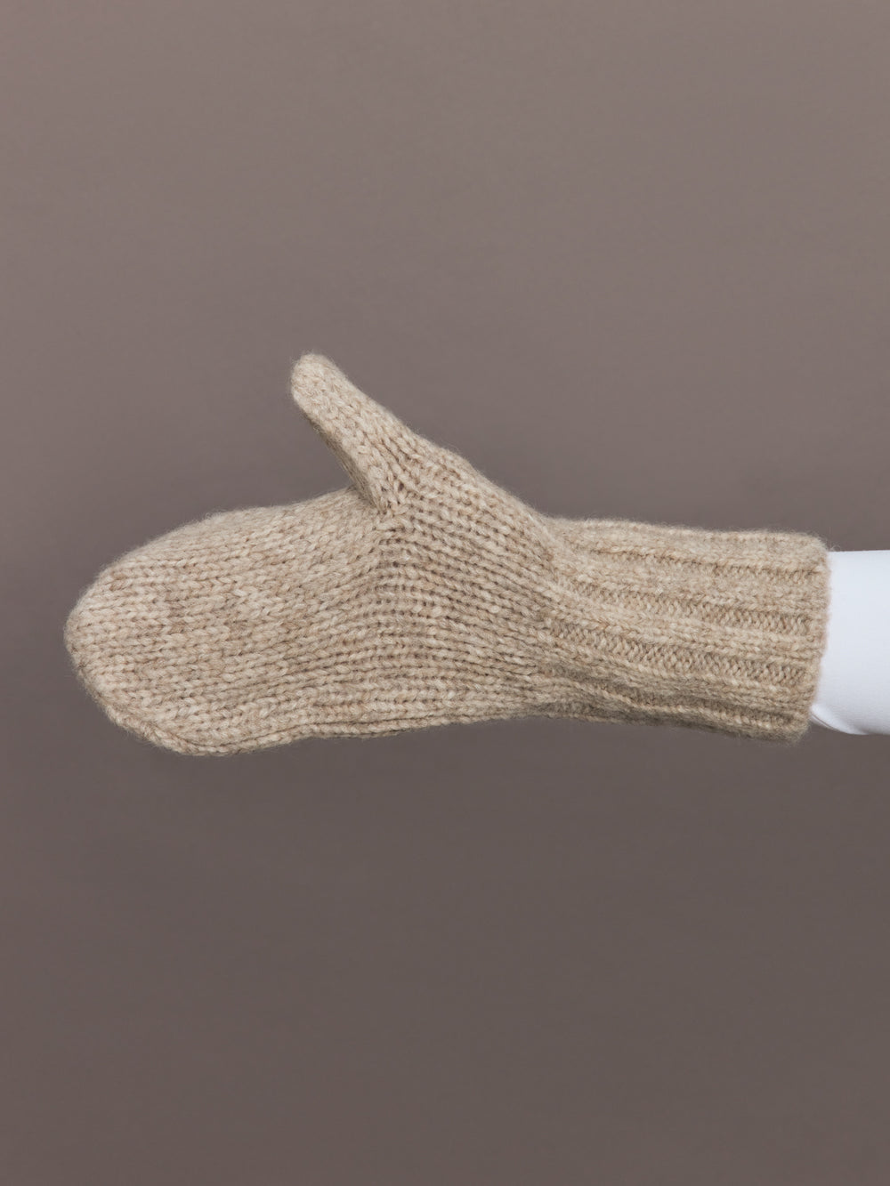 Side view of camel knit mitten showing ribbed cuff detail.