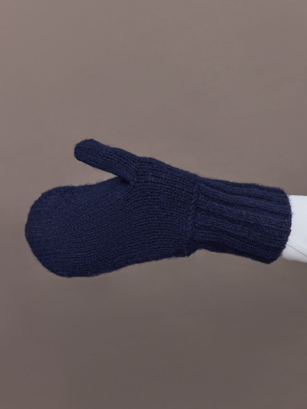 Side view of indigo blue knit mitten showing ribbed cuff detail.