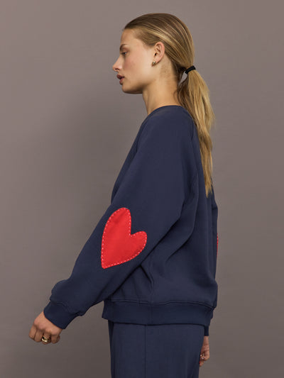 Model is wearing the indigo blue heart patch sweatshirt, front view.