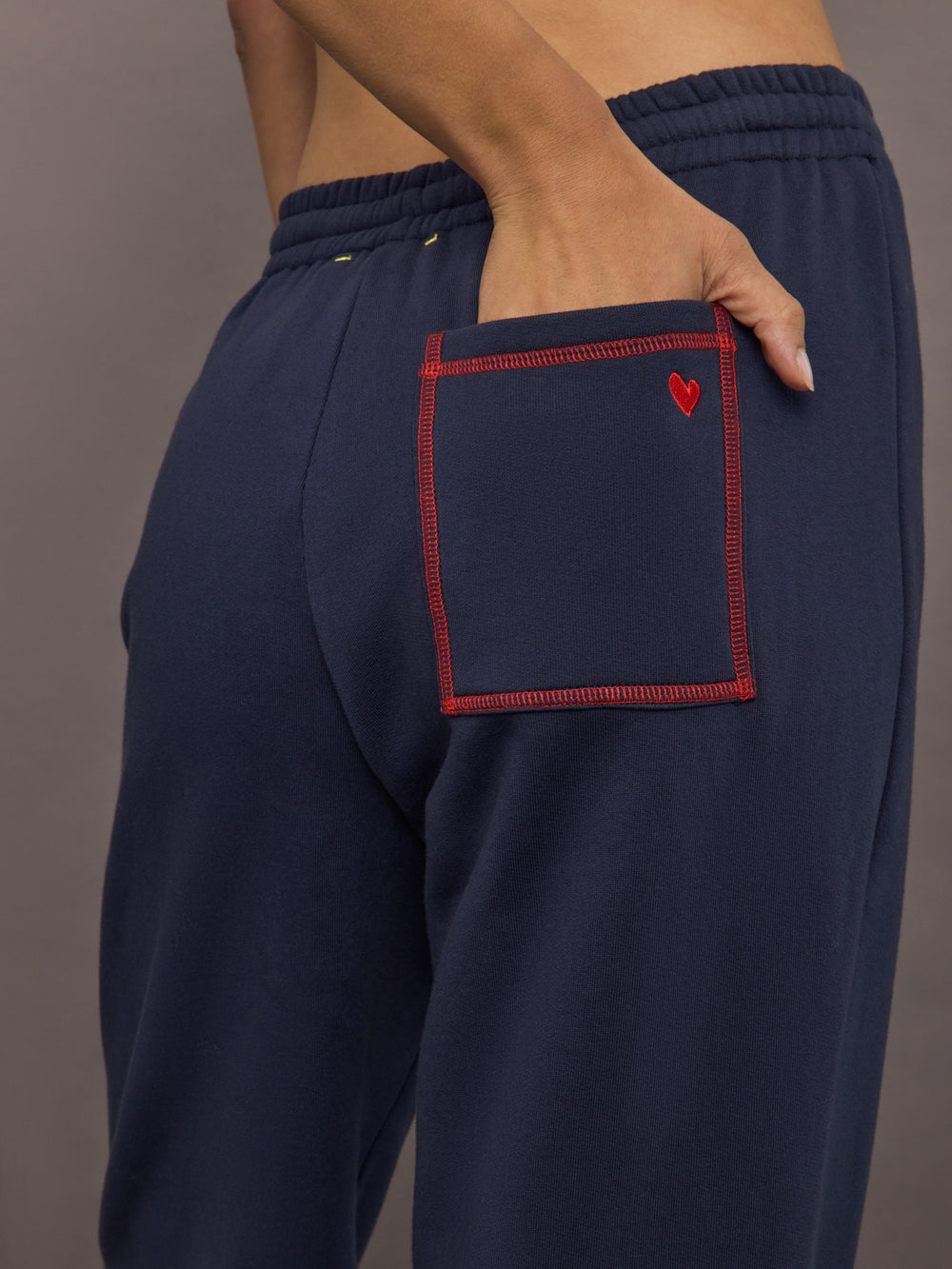 Close-up of back pocket with red stitching and embroidered heart, detail view.