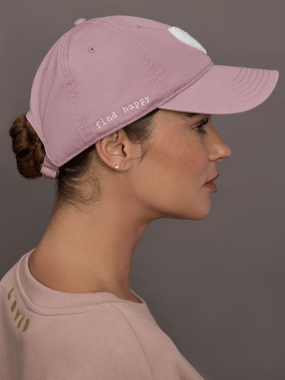 Model is wearing KR Imperfect Chenille Heart Hat in mauve, side view with find happy embroidery.