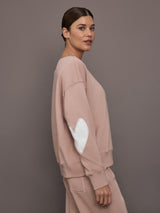 Model is wearing Ex-Boyfriend fleece relaxed crewneck sweatshirt in mauve, side view with elbow patch detail.