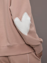 Model is wearing Ex-Boyfriend fleece relaxed crewneck sweatshirt in mauve, close-up of Imperfect Heart patch.