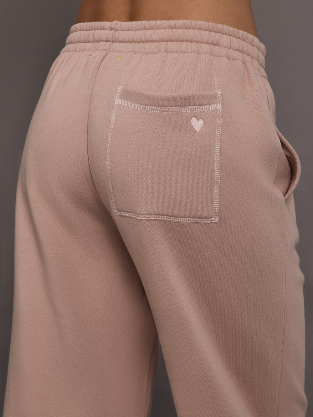 Model is wearing Weekend Barb fleece sweatpant in Mauve, back pocket heart detail close-up.