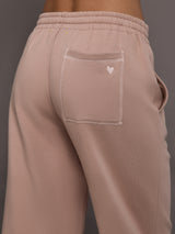 Model is wearing Weekend Barb fleece sweatpant in Mauve, back pocket heart detail close-up.