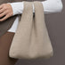 Model wears a double handled taupe linen textured bag on her arm.