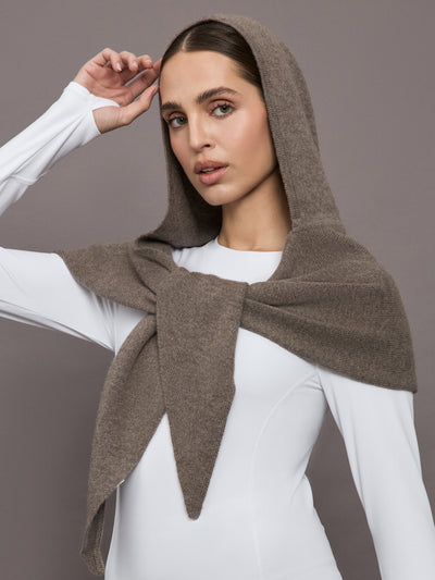 Model wears a muted brown colored hooded scarf over her head. 