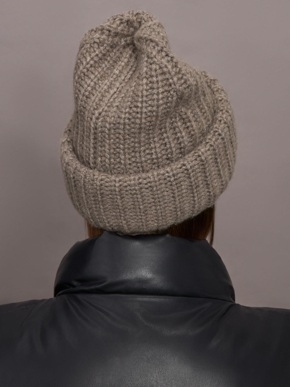 Model wears a light brown thick knit beanie. 