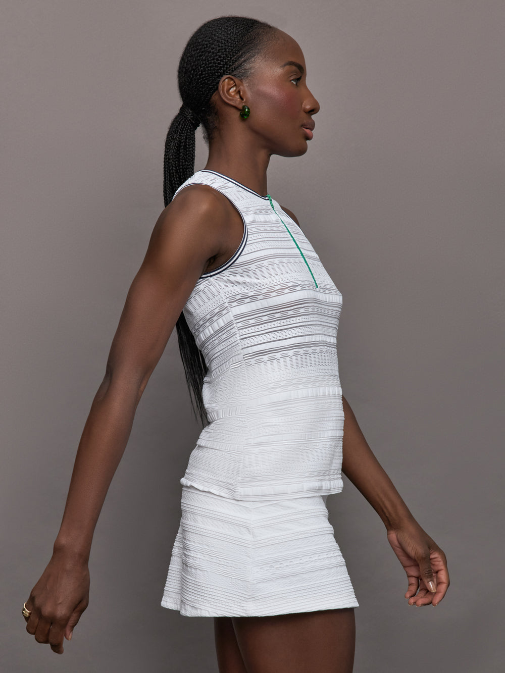 Model wears a semi-fitted white sleeveless tank with green zipper and trim.