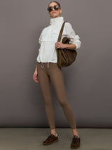 Model is wearing a white windbreaker with drawstrings at the bottom of the jacket and twin chested pockets and a detachable hood. 