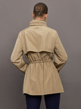 Model is wearing a tan colored rain jacket with a cinched waist.