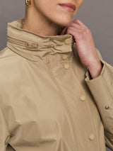 Model is wearing a tan colored rain jacket with a cinched waist.
