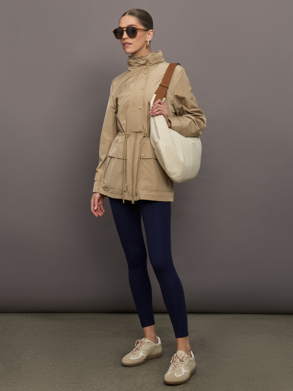 Model is wearing a tan colored rain jacket with a cinched waist.